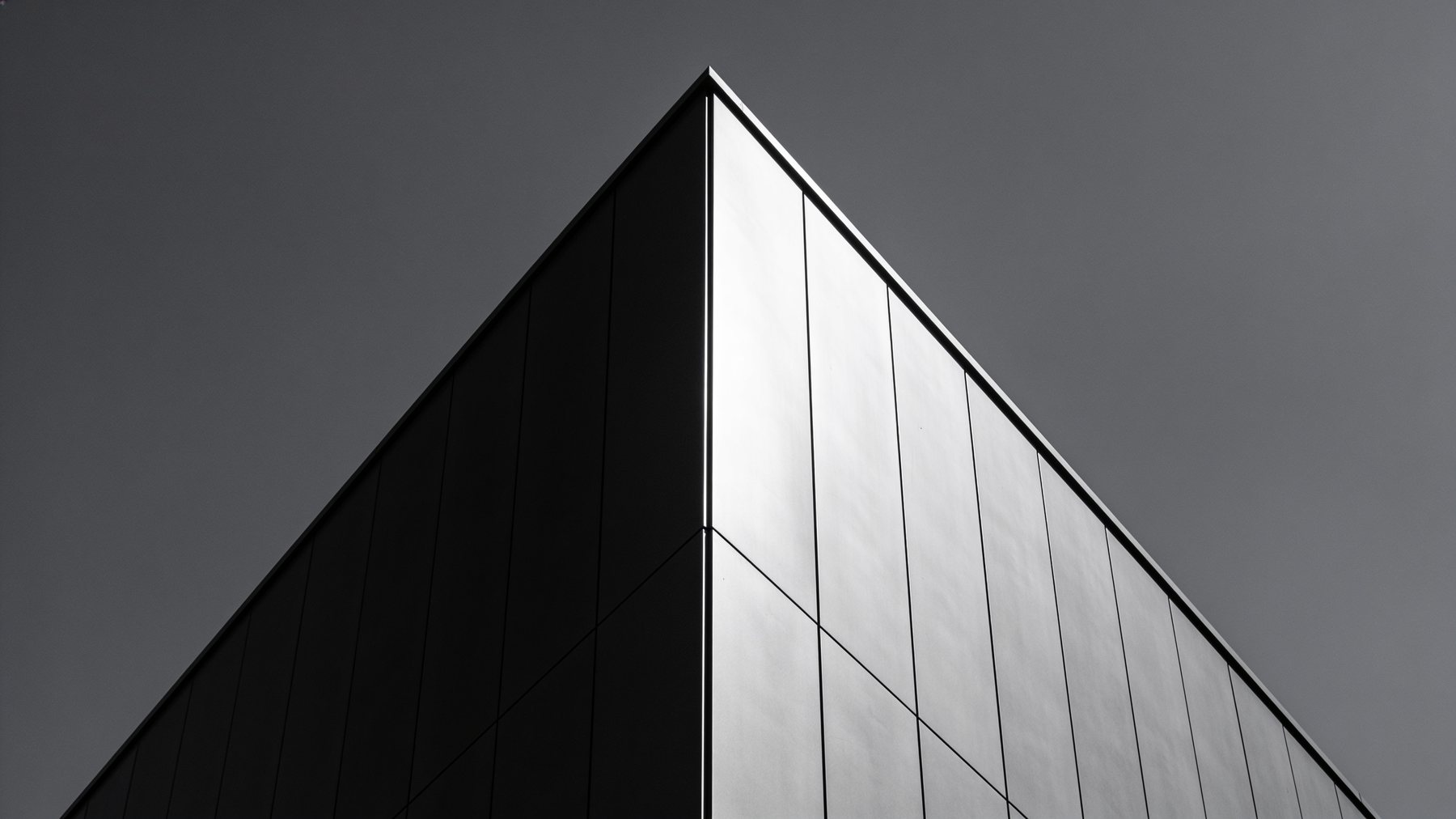 Abstract architectural detail: two planes of brushed metal cladding meeting at a sharp diagonal edge