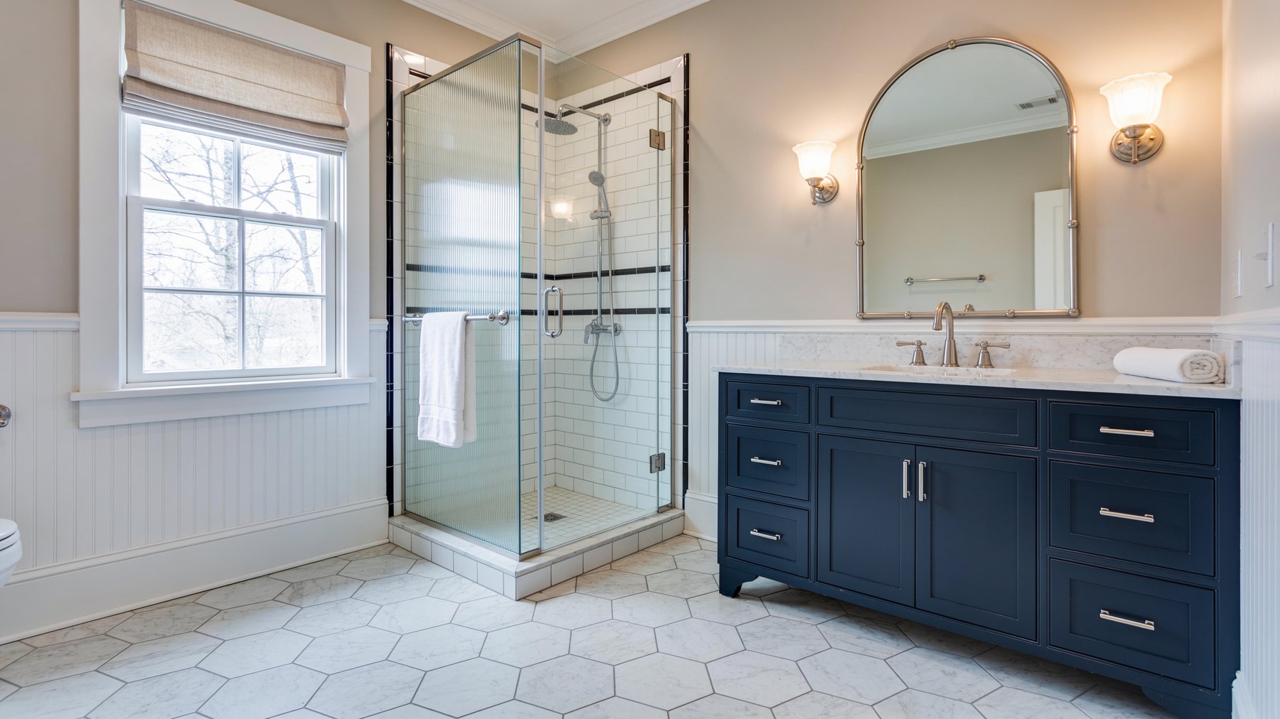 Completed classic guest bathroom with marble hexagon floor, beadboard wainscoting and navy vanity
